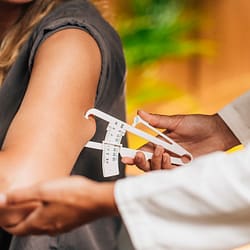 Dietitian measuring body fat, using caliper on the female patient's arm
