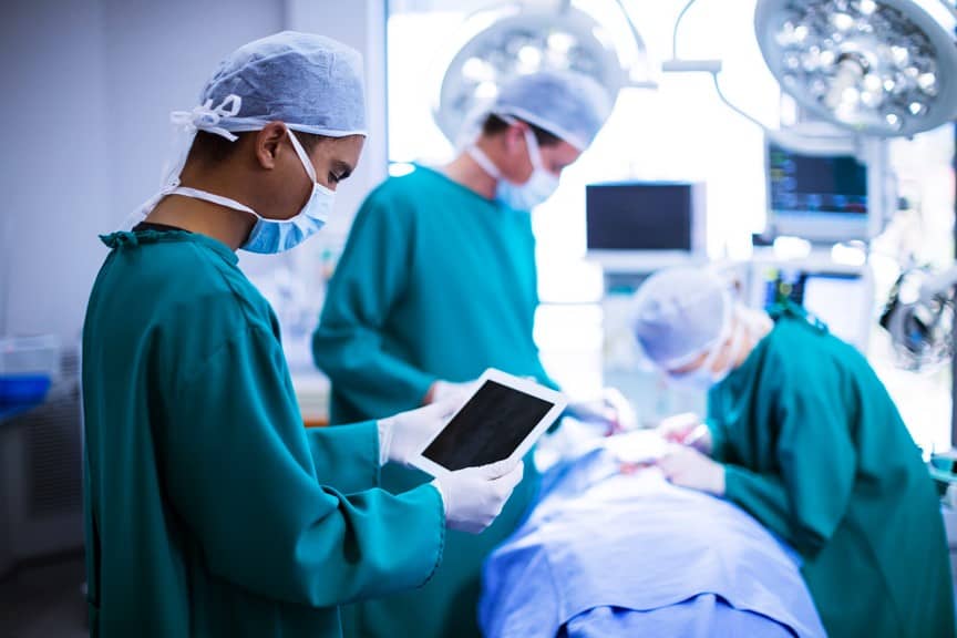 Surgeon using digital tablet in operation of hospital